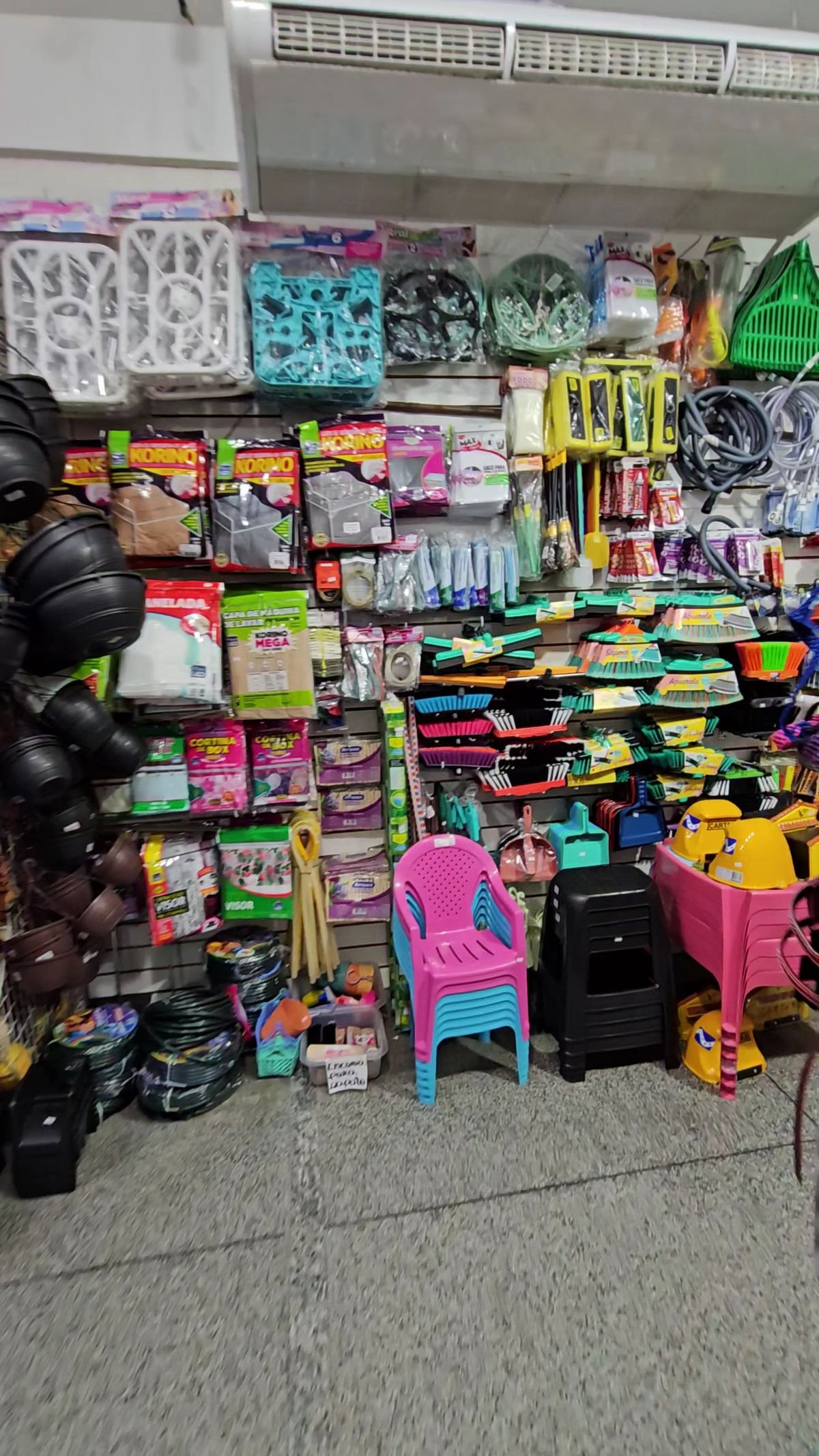Parede da loja com cestos, organizadores, bolsas e cadeirinhas infantis coloridas